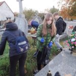 Wolontariusze sprzątają groby