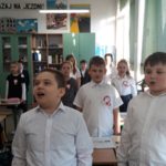 Uczniowie odświętnie ubrani śpiewają hymn