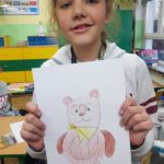 Dziewczynka pokazuje swój rysunek misia