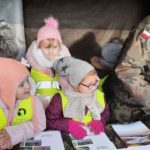 Dzieci oglądają zdjęcia wyłożone przez żołnierza