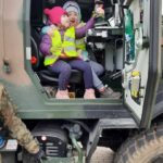 Przedszkolaki siedzą w kabinie samochodu wojskowego