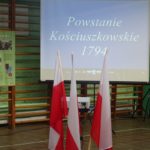 Flagi Polski a w tle ekran z napisem Powstanie kościuszkowskie 1794