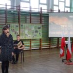 Dziewczynka śpiewa obok flagi Polski