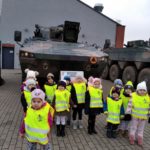 Przedszkolaki stoją na tle samochodu bojowego