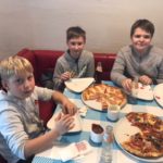 Trzech chłopców spożywa pizzę