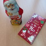 Figurka Mikołaja czekoladowego i obok czekolada w świątecznym opakowaniu