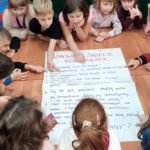 Dzieci czytają treść plakatu Rozmowa o świecie bez książek