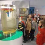 Dzieci po kolei kręcą wirówką z wodą i kolorowymi piłeczkami w Muzeum Mleka w Grajewie