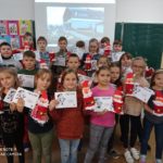Dzieci w swojej klasie pokazują otrzymane z Muzeum Mleka dyplomy i wykonane pojemniki na długopisy z Mikołajem