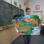 Uczeń trzyma plakat z namalowanymi żubrami