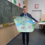 Uczeń trzyma plakat z namalowanymi żubrami