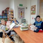 Trzech uczniów wyszukuje informacji w o matematykach w bibliotece miejskiej dla dzieci