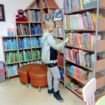 Uczeń stoi przy regale i wyszukuje książek
