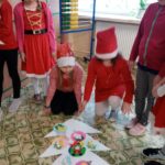 Dziewczynki dekorują kontur choinki bombkąmi z papieru