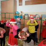 Dzieci ubrane na czerwono i w czapkach Mikołaja ćwiczą