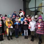 Ubrani trzecioklasiści przed Muzeum Mleka z kubkami ozdobionymi wizerunkiem Mikołaja