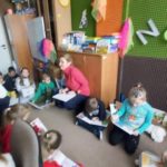 Dzieci z klas 1-3 siedzą na dywanie i czytają książki