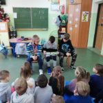 Strasi uczniowie czytają książkę przedszkolakom