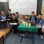 Uczniowie trzymają Pismo święte obok stolik z czterema świecami