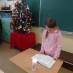 Uczennica przy świecy czyta koleżankolm i kolegom w klasie pismo święte