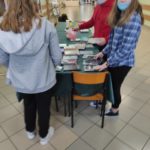 Członkowie Szkolnego Koła Profilaktyków układają książki na stoliku