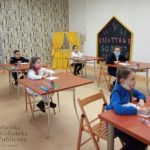 Pięcioro dzieci pisze dyktando w bibliotece miejskiej