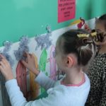 Dzieci przklejają do ściany narysowany płotek z kotami