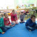 Przedszkolaki siedzą na dywanie i słuchają