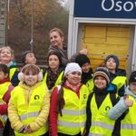 Dzieci w żółtych kamizelka z wychowawczynią stoją na dworcu PKP w Osowcu