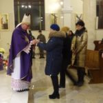 Kobieta przekazuje dary biskupowi podczas mszy świętej