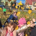 Radosne dzieci podrzucają żółte liście