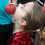 Dziewczynka gryzie jabłko zawieszone na wstążce