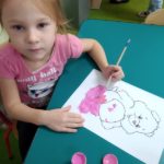 Dziewczynka maluje farbami misia