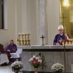Biskup przemawia podczas mszy przez mikrofon do parafian