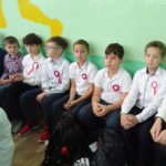 Narodowe Święto Niepodległości w SP 4 - uczniowie ubrani na galowo i z kotylionami oglądają akademię