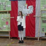 Narodowe Święto Niepodległości w SP 4 - uczennica na tle dekoracji recytuje wiersz patriotyczny
