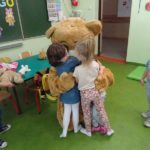 Dzieci przytulają się do dużego pluszowego misia