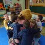 Dzieci przytulają się do dużego pluszowego misia