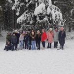 Zimowa wyprawa klas piątych - dzieci na tle zaśnieżonych drzew