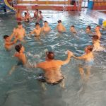 Andrzejki na Pływalni Miejskiej - dzieci w kółku z instruktorem bawią się w wodzie