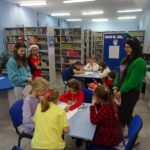Mikołajki w bibliotece - uczestnicy spotkania rysują w grupach Mikołaje