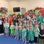 Grupa przedszkolaków i straszych uczniów ubranych na zielono