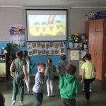 Przedszkolaki patrzą na ekran i naśladując tańczą