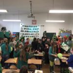 Uczniowie ubrani na zielono w klasie i z transparentem